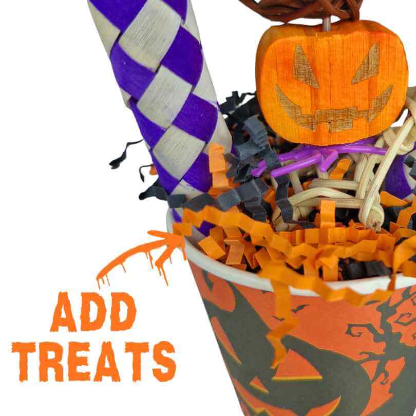 Close-up of treats being added among the shredded paper inside the Halloween Parrot Treat Cup